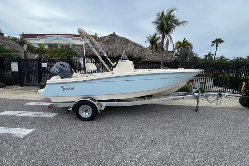 The Image of 2027 Scout 188 Sportfish boat on trailer, parked near tropical setting with palm trees. - 0