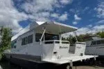 Slide: The Image of White 1982 Masterfab 65 houseboat under a partly cloudy sky. - 2