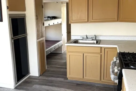 Slide: The Image of Compact kitchen in a 1982 Masterfab 65 mobile home with wood cabinets and bunk beds. - 5