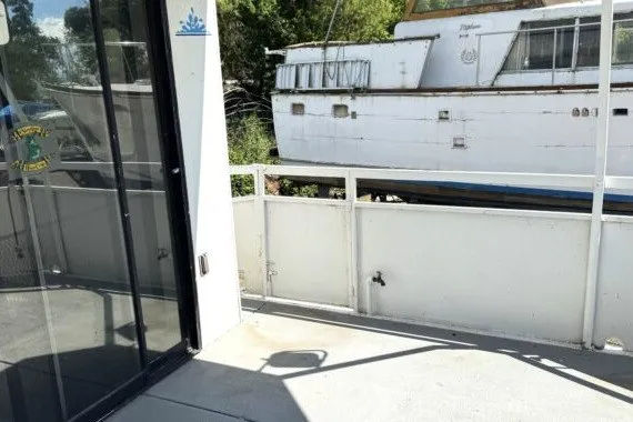 Slide: The Image of Outdoor deck view of a 1982 Masterfab 65 houseboat with railing and nearby boat. - 8