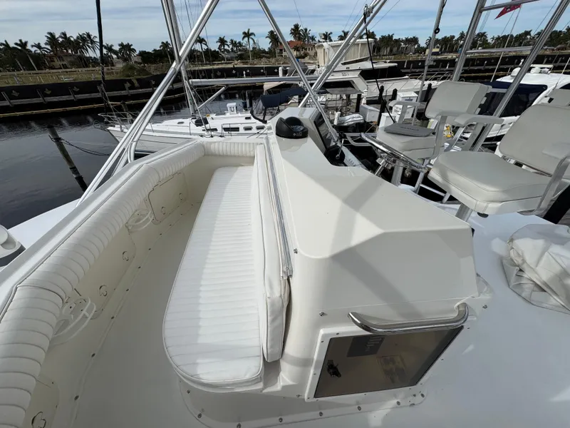 Slide: The Image of 1999 Cabo 45 Express yacht interior with white seating and helm, docked at marina. - 31