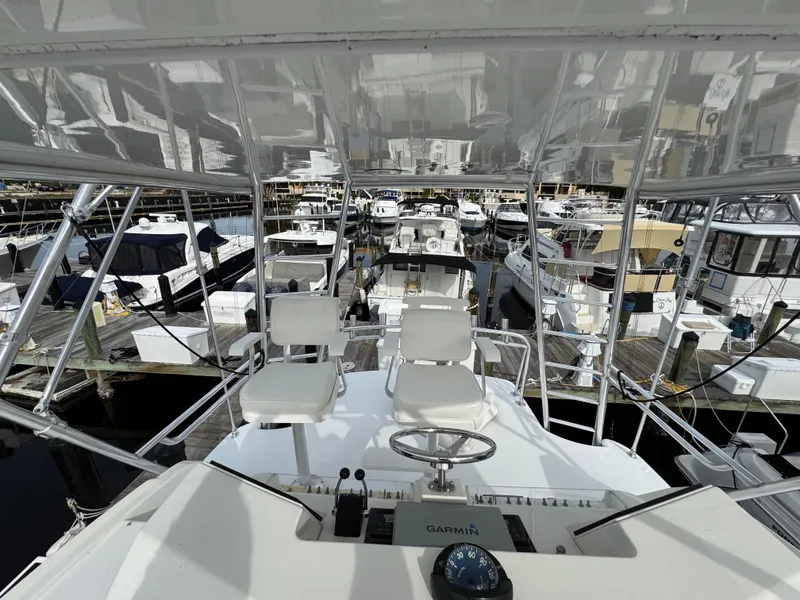 Slide: The Image of 1999 Cabo 45 Express yacht helm with marina view, featuring dual seats and navigation equipment. - 32