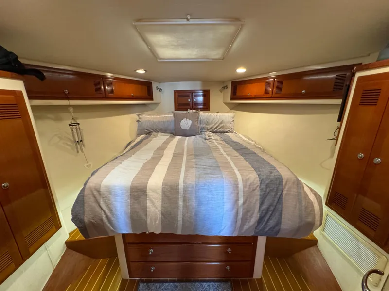 Slide: The Image of Cozy cabin interior of 1999 Cabo 45 Express with striped bedding and wooden storage. - 40