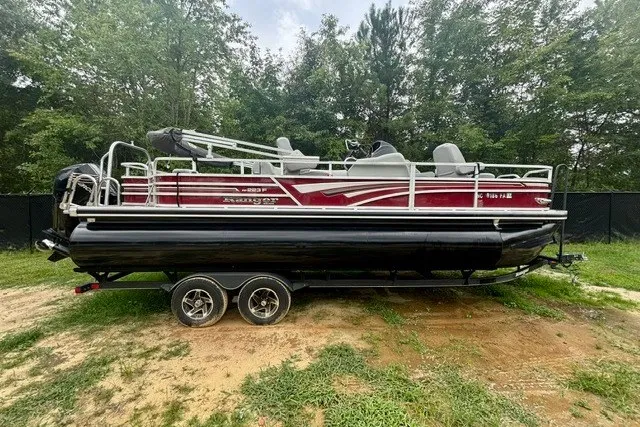 Slide: The Image of 2023 Ranger 223F pontoon boat with red and black design, parked on grass. - 1