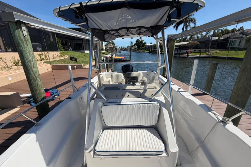 Slide: The Image of 1995 Pro-Line 21 Sport boat docked by waterfront homes, featuring white seating and canopy. - 18