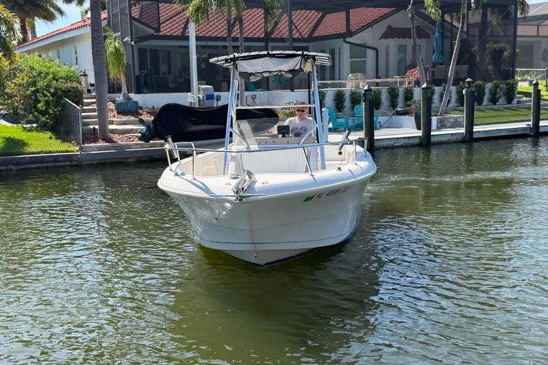 Slide: The Image of 1995 Pro-Line 21 Sport boat cruising on a sunny waterfront near a house. - 7