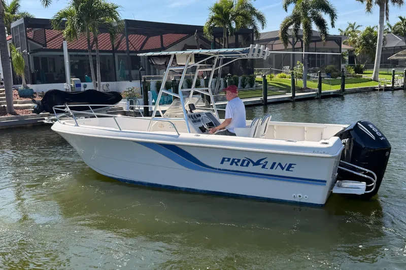Slide: The Image of 1995 Pro-Line 21 Sport boat on water, with a person steering near a dock. - 3