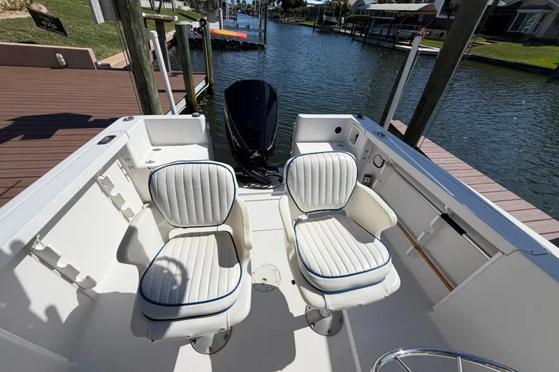 Slide: The Image of 1995 Pro-Line 21 Sport boat interior with two white cushioned seats by the water. - 14