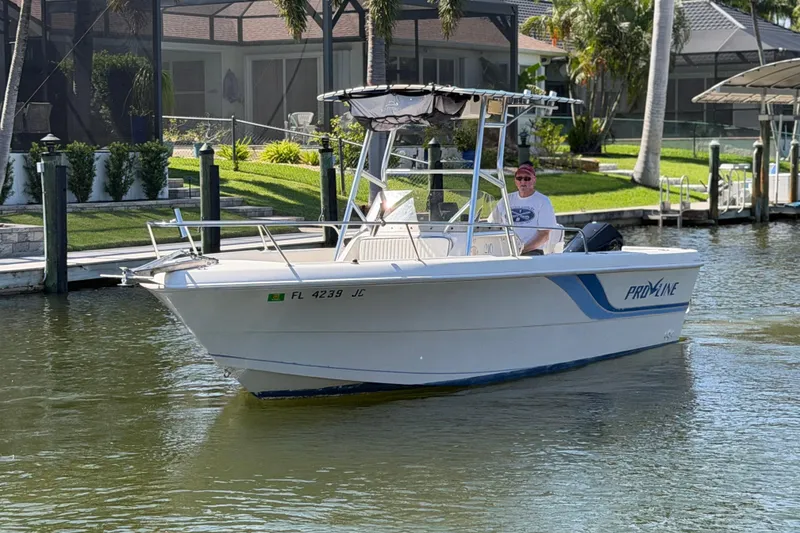 Slide: The Image of 1995 Pro-Line 21 Sport boat cruising on a sunny canal near waterfront homes. - 6