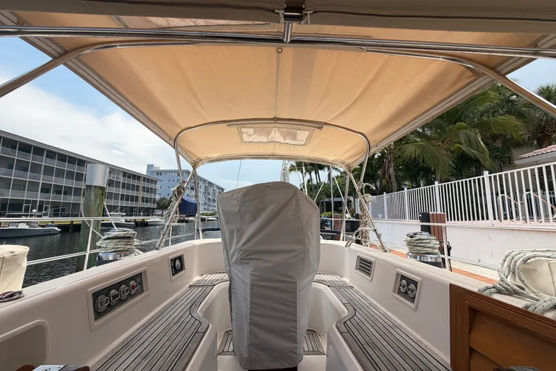 Slide: The Image of 2009 Hylas 54 sailboat cockpit with canopy, docked near waterfront buildings and palm trees. - 26