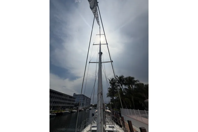 Slide: The Image of Sailboat mast of 2009 Hylas 54 under cloudy sky, docked near palm trees. - 35