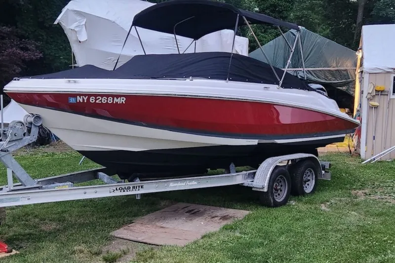 Slide: The Image of 2020 Regal 21 OBX boat on trailer, red and white, covered, parked on grass. - 4