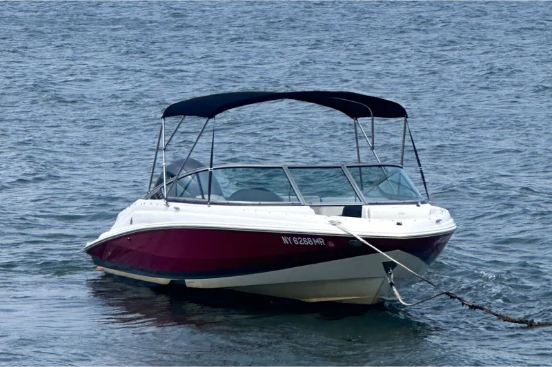 Slide: The Image of 2020 Regal 21 OBX boat with canopy, anchored on calm water. - 2