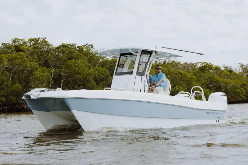 Slide: The Image of 2026 World Cat 235TE boat cruising on water near lush greenery. - 29