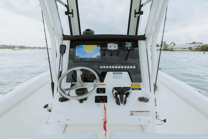 Slide: The Image of 2026 World Cat 235TE boat dashboard with steering wheel and navigation screens on open water. - 40