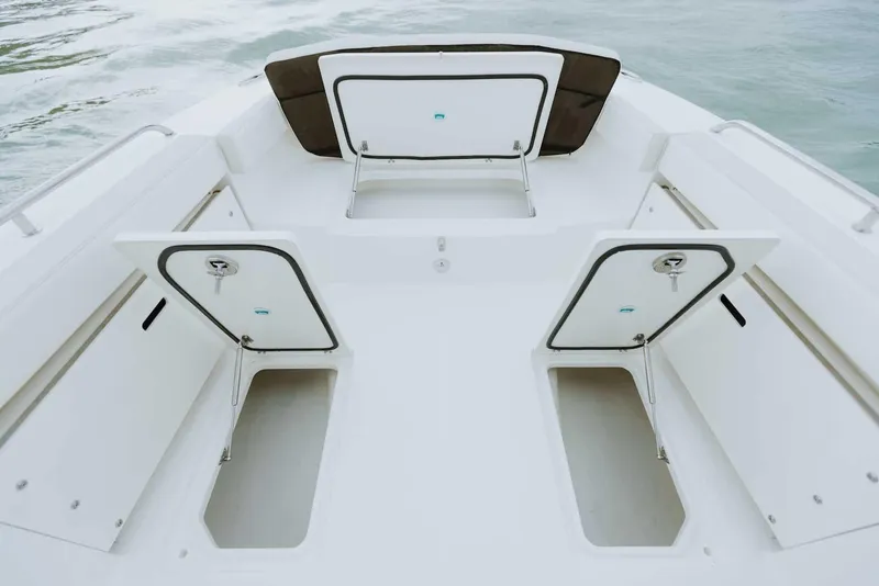 Slide: The Image of 2026 World Cat 235TE boat deck with open storage compartments on calm water. - 33