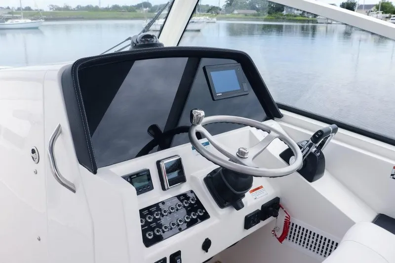 Slide: The Image of 2026 World Cat 325DC boat helm with steering wheel and control panel. - 21