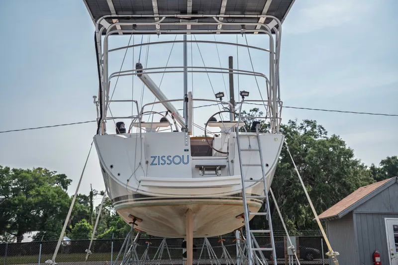 Slide: The Image of 2015 Bavaria Vision 46 sailboat on dry dock, rear view with trees and shed. - 39