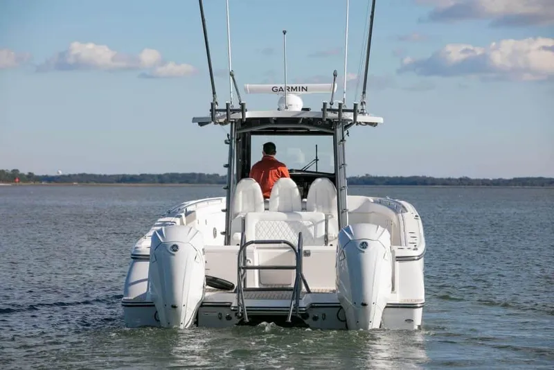 Slide: The Image of 2026 World Cat 400CC-X boat on water, rear view, clear sky, person steering. - 7