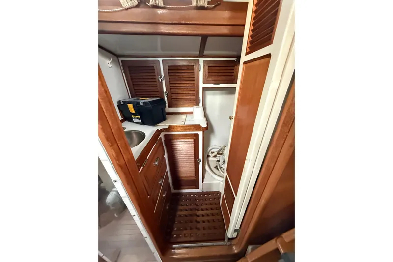 Slide: The Image of Compact wooden boat interior with sink, storage cabinets, and nautical equipment, Custom 46, 1990 model. - 15