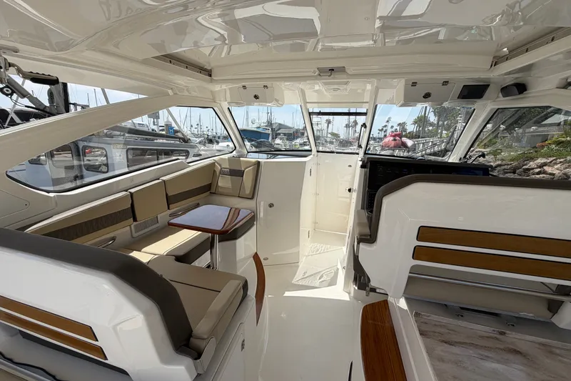 Slide: The Image of 2019 Pursuit DC 365 Dual Console interior with seating and table, docked at marina. - 24