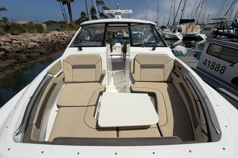 Slide: The Image of 2019 Pursuit DC 365 Dual Console boat with spacious seating and table in a marina. - 67