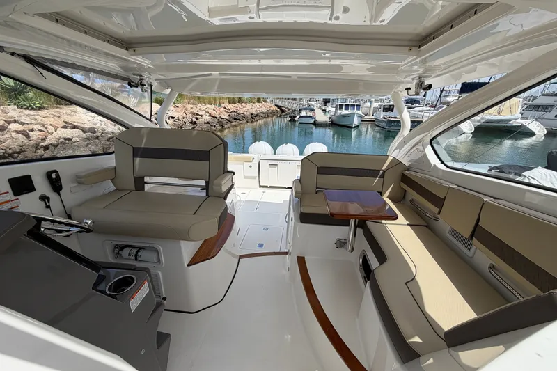 Slide: The Image of 2019 Pursuit DC 365 Dual Console boat interior with seating and table, docked at marina. - 36