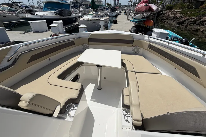 Slide: The Image of 2019 Pursuit DC 365 Dual Console boat with beige seating and table at marina. - 66
