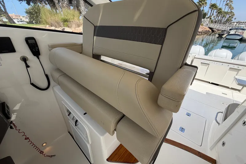 Slide: The Image of 2019 Pursuit DC 365 Dual Console boat interior with beige seating and control panel. - 38