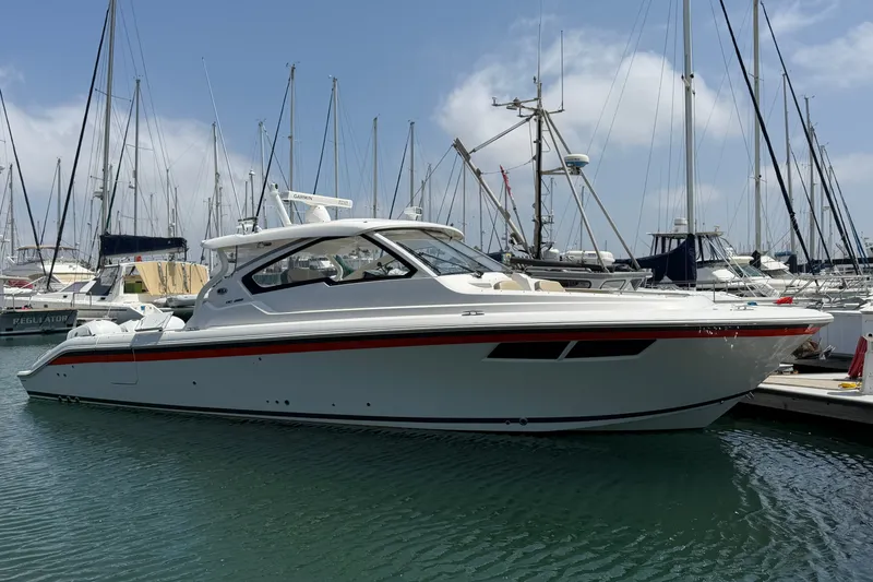 The Image of 2019 Pursuit DC 365 Dual Console boat docked in marina with sailboats. - 0