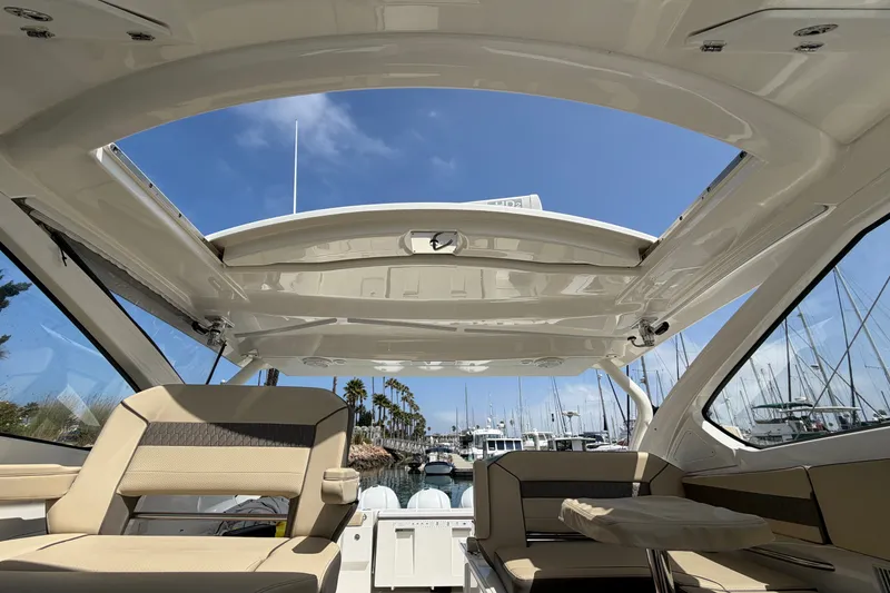Slide: The Image of 2019 Pursuit DC 365 Dual Console boat interior with open roof, docked at marina. - 43