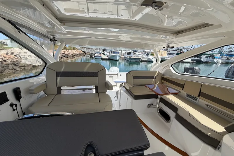 Slide: The Image of 2019 Pursuit DC 365 Dual Console interior with seating and table, docked at marina. - 35