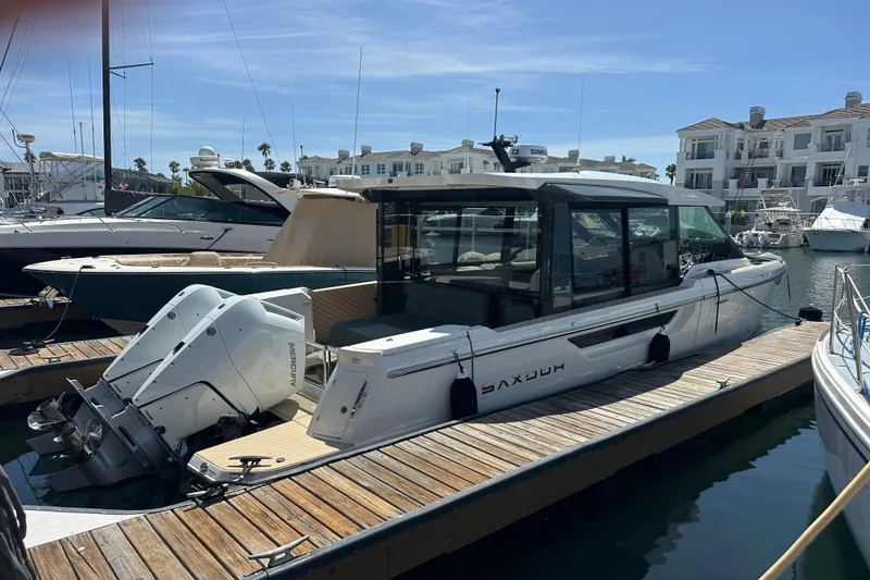 The Image of 2027 Saxdor 400 GTC boat docked at marina, featuring sleek design and powerful Mercury engines. - 0