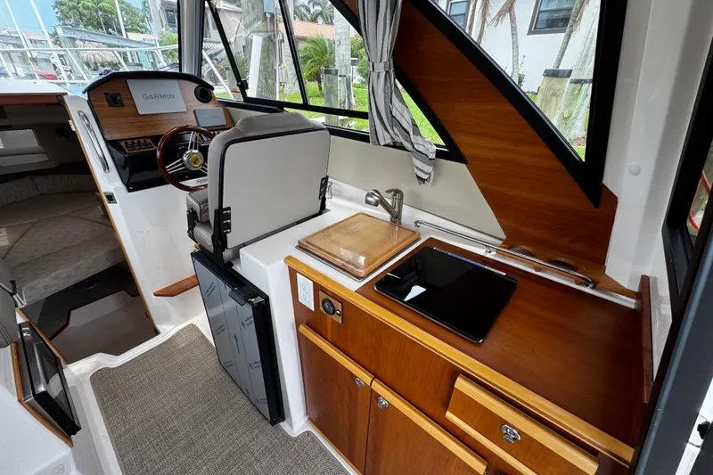 Slide: The Image of 2024 Cutwater C-248 Coupe interior with helm, kitchenette, and seating area. - 6