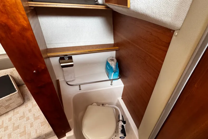 Slide: The Image of 2024 Cutwater C-248 Coupe bathroom with toilet, wooden paneling, and storage shelves. - 10