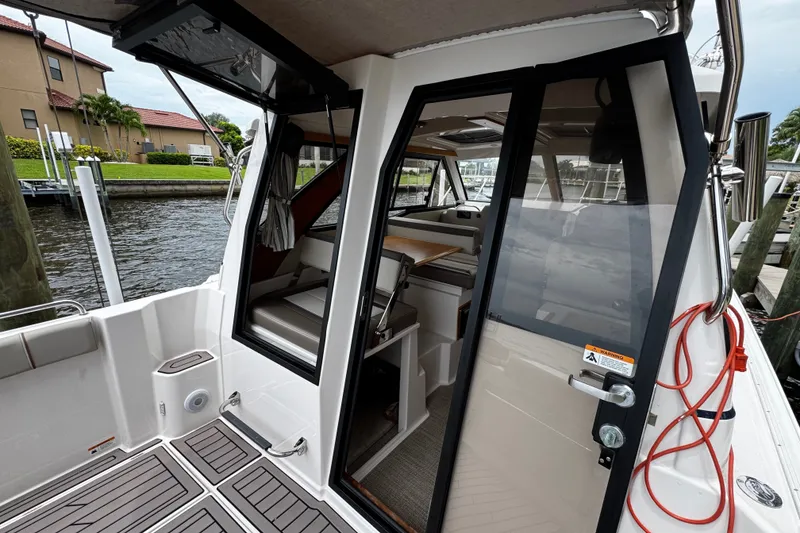 Slide: The Image of 2024 Cutwater C-248 Coupe boat interior with open door, docked by a canal. - 1