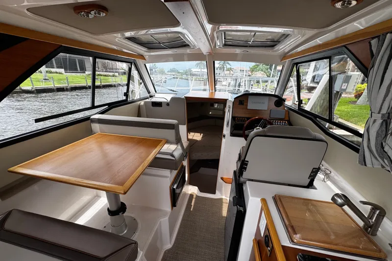 Slide: The Image of 2024 Cutwater C-248 Coupe interior with dining table, helm, and kitchenette. - 3
