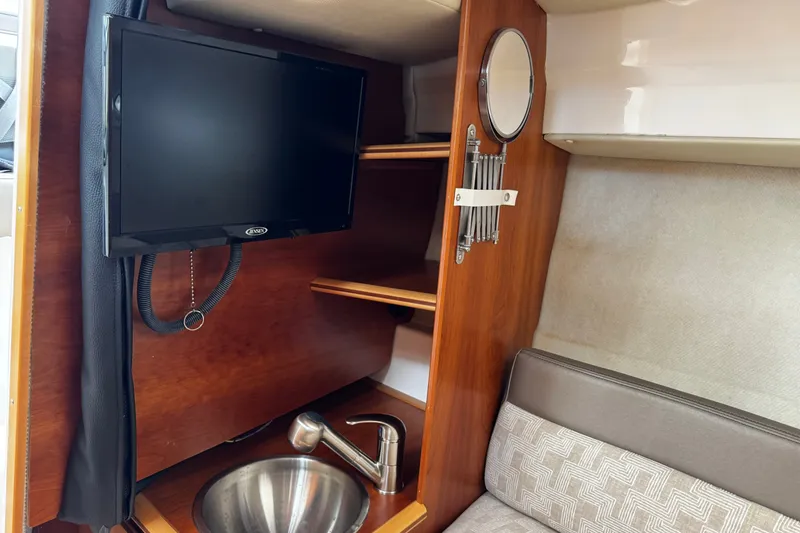 Slide: The Image of 2024 Cutwater C-248 Coupe interior with TV, sink, and wooden shelving. - 9