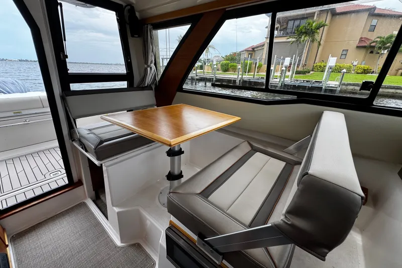 Slide: The Image of 2024 Cutwater C-248 Coupe interior with dining area, featuring a wooden table and cushioned seating. - 5