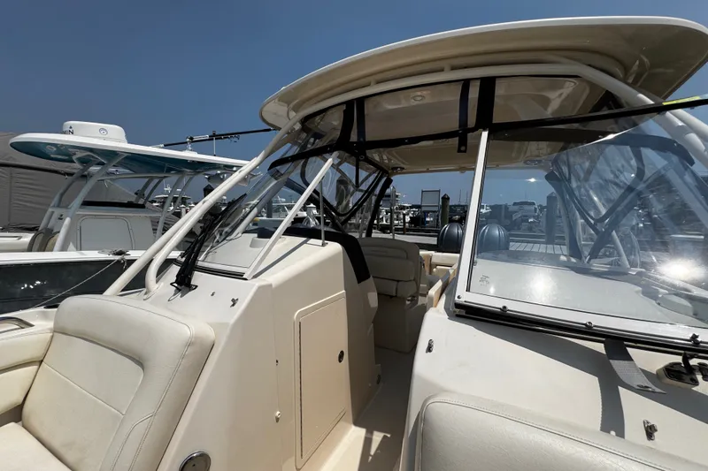 Slide: The Image of 2022 Grady-White Freedom 285 boat interior with seating and windshield, docked under clear sky. - 16