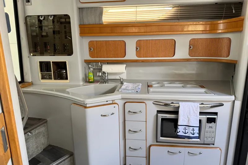 Slide: The Image of Interior of 1990 Sea Ray 420 Sundancer yacht kitchen with modern appliances and wooden cabinetry. - 14