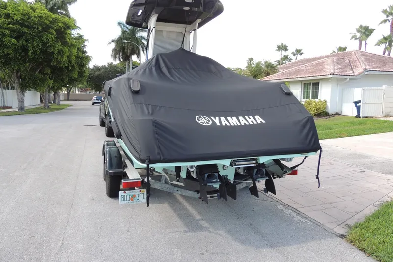 Slide: The Image of 2023 Yamaha Boats 222 FSH Sport E covered on trailer in suburban street. - 2
