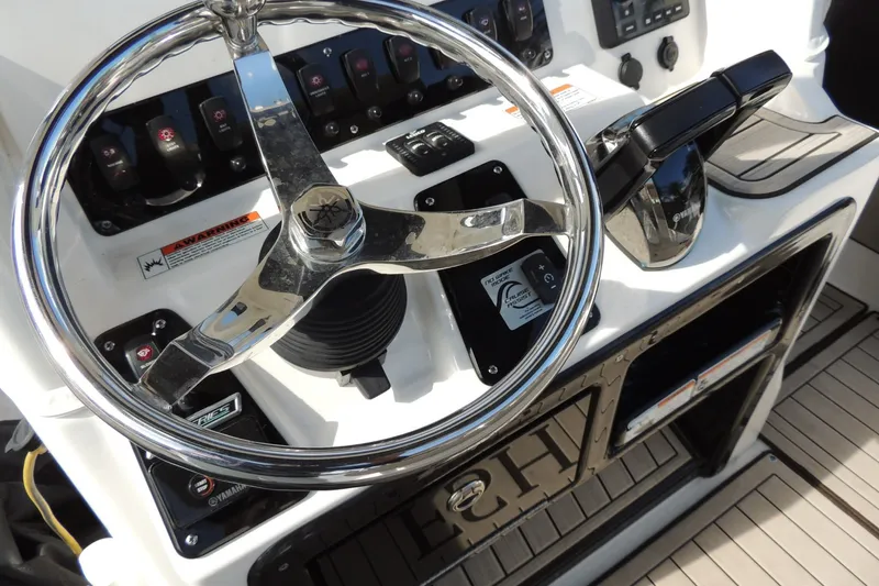 Slide: The Image of 2023 Yamaha Boats 222 FSH Sport E steering console with chrome wheel and controls. - 4