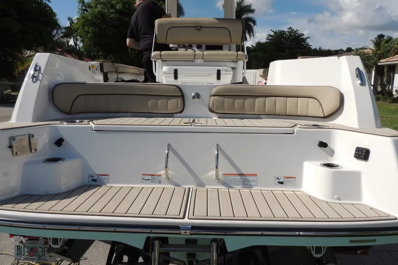 Slide: The Image of 2023 Yamaha Boats 222 FSH Sport E, rear view with seating and deck, outdoors. - 10