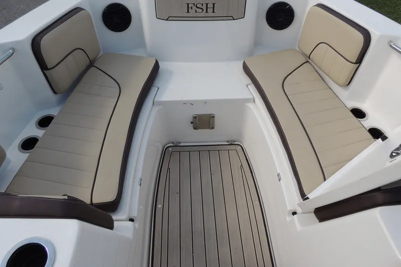 Slide: The Image of 2023 Yamaha Boats 222 FSH Sport E interior with beige seating and wood-style flooring. - 7