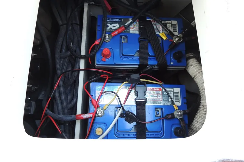 Slide: The Image of 2023 Yamaha Boats 222 FSH Sport E battery compartment with dual blue batteries. - 14