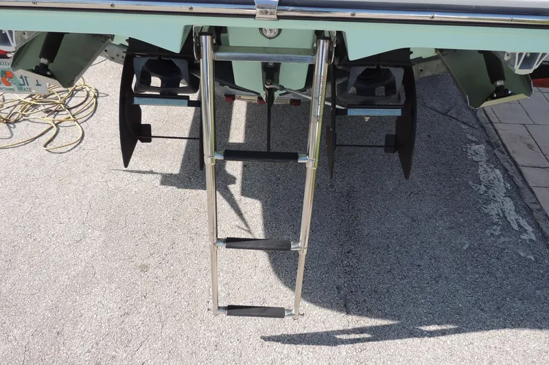Slide: The Image of 2023 Yamaha Boats 222 FSH Sport E with rear ladder on pavement. - 28
