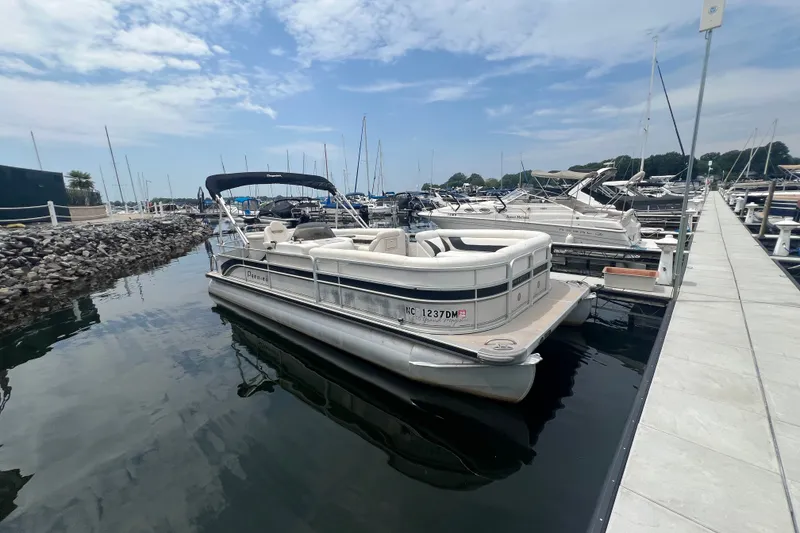 The Image of 2007 Premier 250 Grand Majestic pontoon boat docked at a marina under a partly cloudy sky. - 0