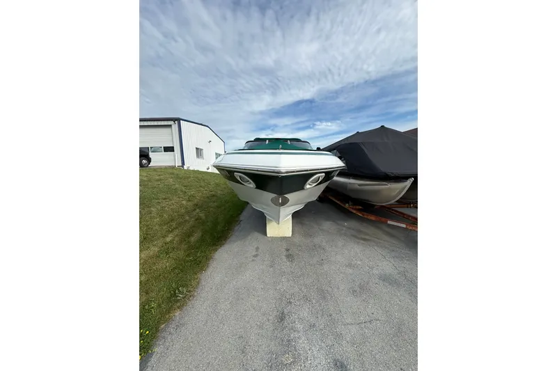 Slide: The Image of 1996 Cobalt 272 boat on trailer, parked near a building under a cloudy sky. - 32