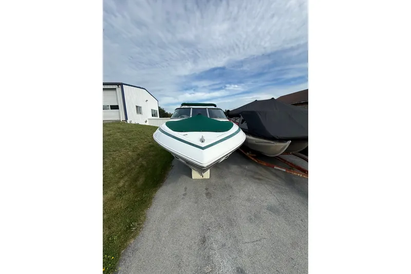 Slide: The Image of 1996 Cobalt 272 boat with green cover, parked on a driveway near a building. - 34